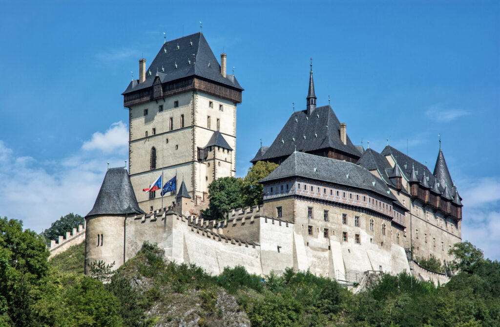 Karlstejn Castle sits upon a craggy hill beneath blue skies