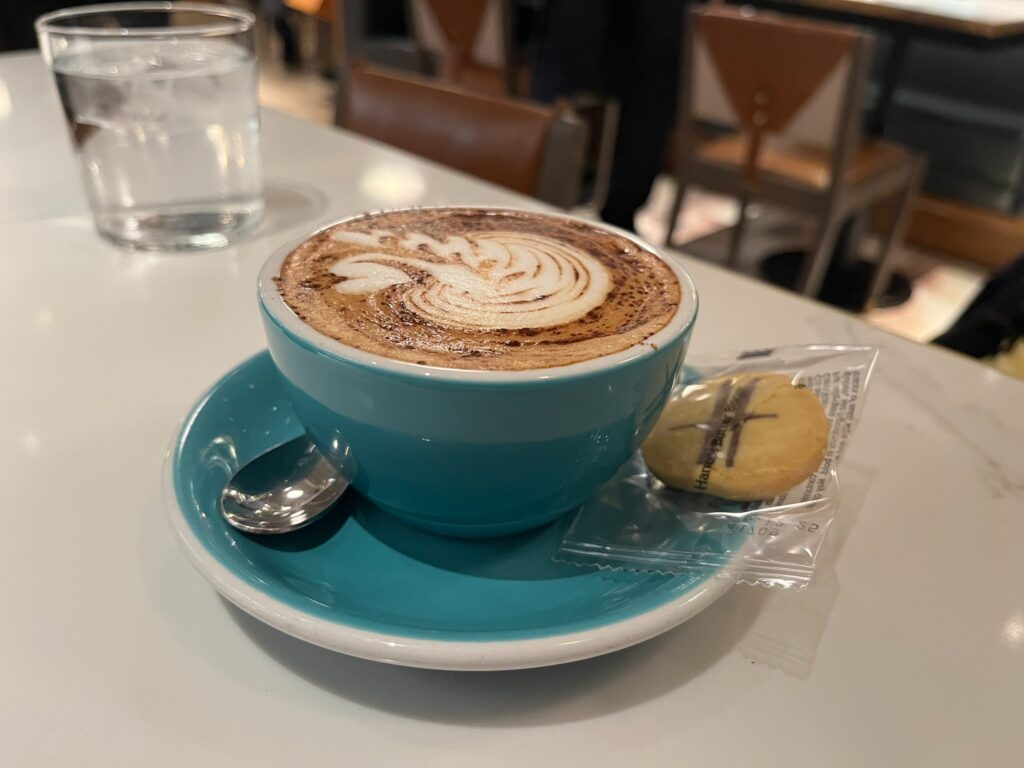 Cup of coffee with a Harrods H biscuit at a café in London.