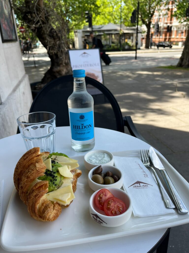 Croissant sandwich with avocado, tomatoes and olives at an outdoor café in London.