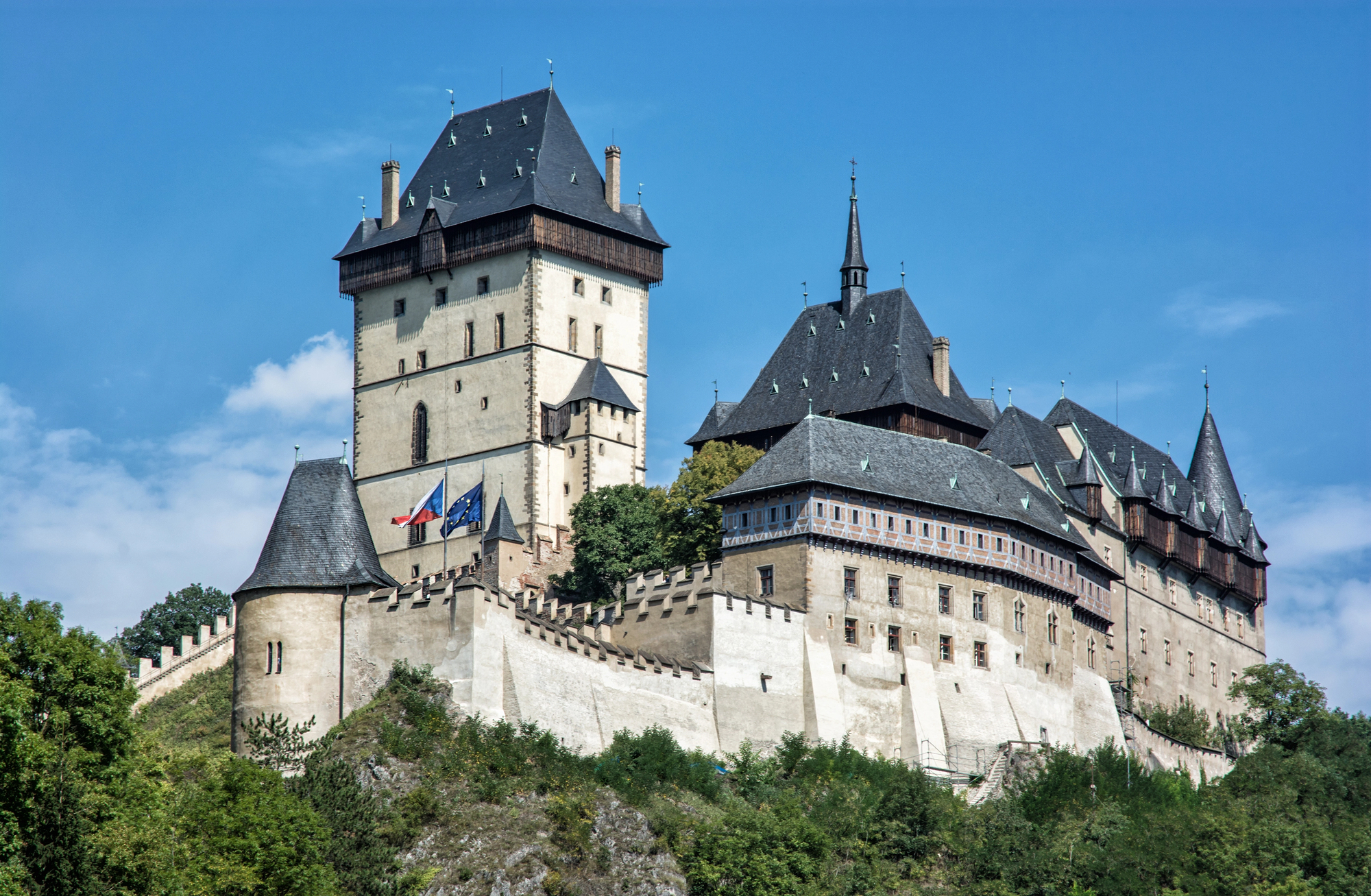 Karlstejn Castle sits upon a craggy hill beneath blue skies