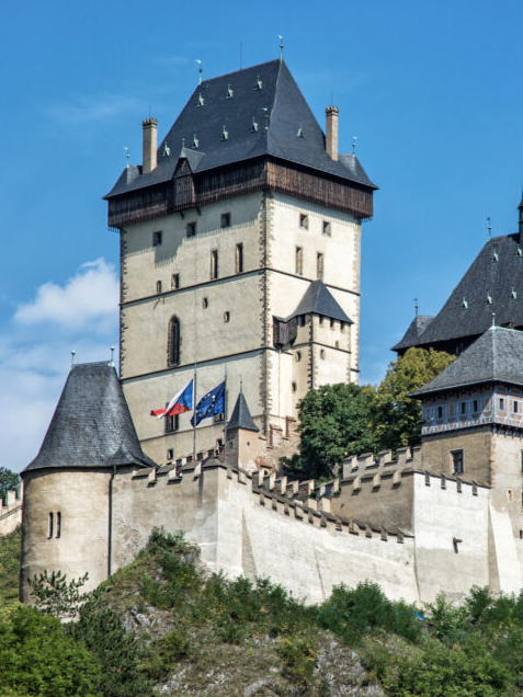 Karlštejn Castle’s fortified towers and stone walls beneath a blue sky in the Czech Republic.